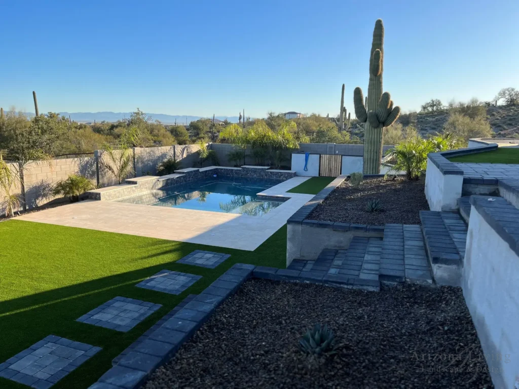 Backyard landscaping around pool with travertine deck, synthetic turf, desert landscaping, and saguaro cactus in San Tan Valley, AZ — designed by Arizona Living Landscape & Design