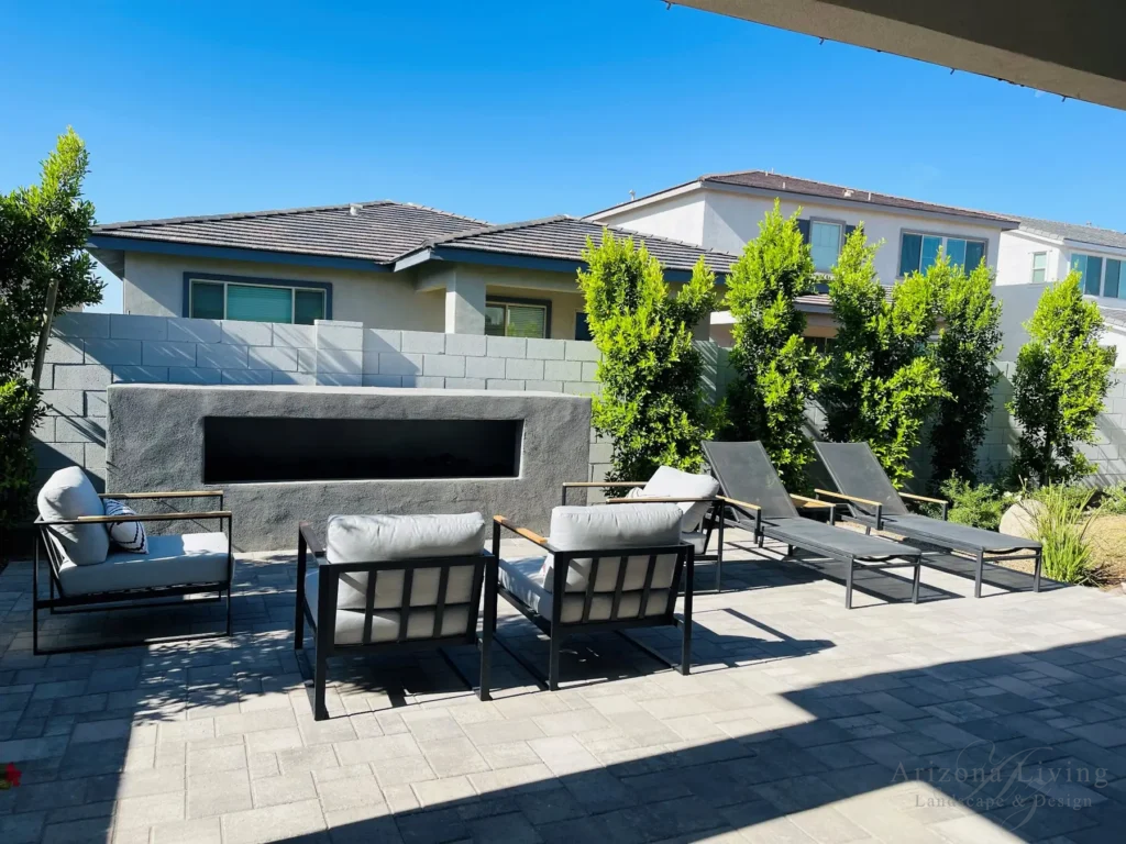 Modern backyard patio with paver flooring, lounge seating, and fireplace and pergolal in San Tan Valley, AZ — built by Arizona Living Landscape & Design